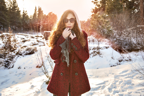 Frau mit Sonnenbrille auf einem schneebedeckten Feld, lizenzfreies Stockfoto