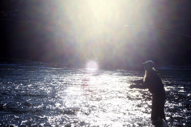 Side view of woman fishing in lake on sunny day - CAVF00014