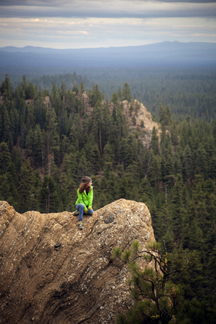 High angle view of hiker sitting on cliff against forest stock photo