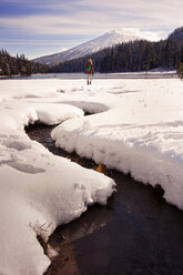 Woman standing on snow covered field against sky - CAVF00067