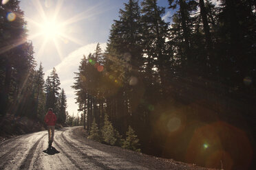 Woman jogging on road amidst trees during sunny day - CAVF00079