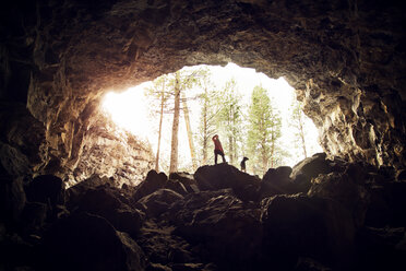 Frau mit Hund auf Felsen in Höhle stehend - CAVF00084