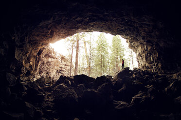 Frau steht auf Felsen in einer Höhle im Wald - CAVF00085