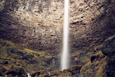 Niedriger Blickwinkel eines Wanderers, der einen Wasserfall betrachtet, während er auf einem Felsen im Wald steht - CAVF00090