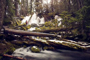 Wanderer, der im Winter im Wald vor einem Wasserfall steht - CAVF00093