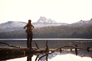 Female hiker standing at lakeshore against mountains - CAVF00123