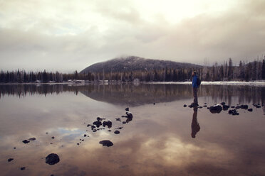 Man standing on rock at Sparks Lake against cloudy sky - CAVF00148