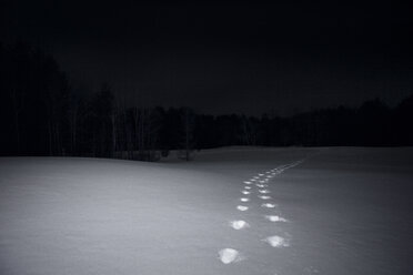 Footprints on snow covered field against sky at night - CAVF00152
