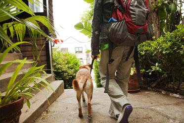 Rückansicht von Frau und Hund auf dem Gehweg - CAVF00168