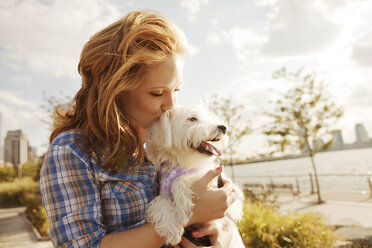 Woman kissing dog against sky on sunny day - CAVF00185