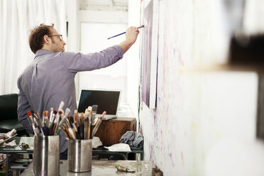 Männlicher Künstler malt im Atelier auf Leinwand - CAVF00272