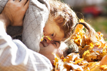 Cheerful father and daughter playing on leaves - CAVF00277