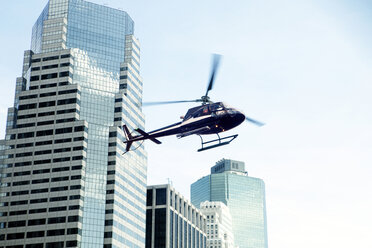 Low angle view of helicopter against modern buildings in city - CAVF00296
