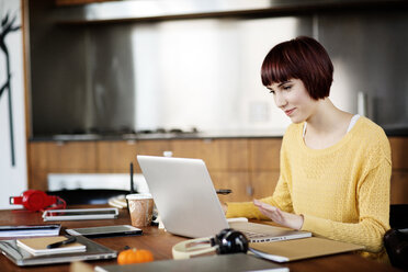 Konzentrierte Geschäftsfrau mit Laptop am Schreibtisch im Kreativbüro - CAVF00307