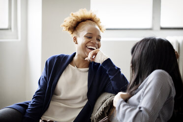 Happy businesswoman looking at colleague while sitting in creative office - CAVF00313