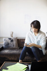 Businesswoman text messaging while sitting on couch in creative office - CAVF00357