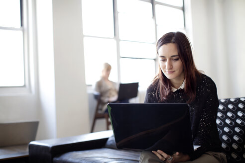 Junge Geschäftsfrau mit Laptop im Kreativbüro - CAVF00358