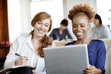 Glückliche Geschäftsfrauen mit Laptop im Büro - CAVF00365