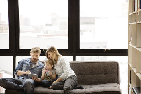 Familie benutzt Tablet-Computer, während sie zu Hause auf dem Sofa sitzt - CAVF00415
