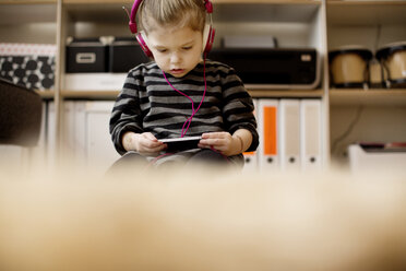 Girl listening to music while using phone at home - CAVF00420