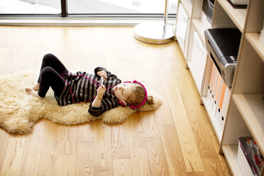 Hoher Blickwinkel von Mädchen hören Musik beim Entspannen auf Teppich zu Hause - CAVF00421
