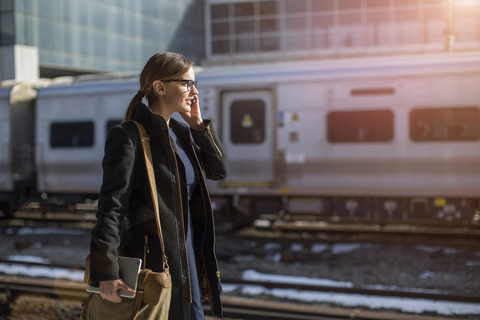 Woman talking on phone while walking at railroad station stock photo