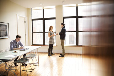 Businessman using phone while colleagues having discussion in background - CAVF00441