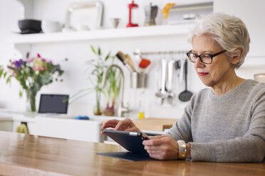 Frau benutzt Tablet-Computer, während sie am Tisch sitzt - CAVF00455