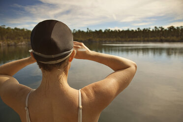 Rückansicht einer Frau mit Badekappe, die am See steht - CAVF00475