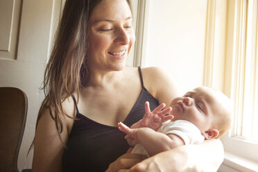 Happy mother carrying baby girl at home - CAVF00492