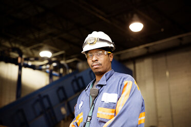 Portrait of male worker standing in illuminated recycling plant - CAVF00498