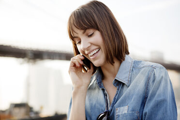 Nahaufnahme einer glücklichen Frau, die ein Mobiltelefon benutzt - CAVF00542