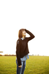 Cheerful woman standing on grassy field at park against clear sky - CAVF00551