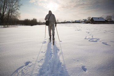 Rückansicht eines Mannes beim Skifahren auf einem schneebedeckten Feld - CAVF00564