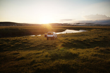 Car parked on field by river during sunset - CAVF00577