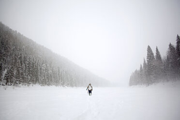 Rear view of hiker walking on snow covered field - CAVF00594