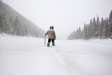 Rückansicht eines Mannes beim Wandern auf einem schneebedeckten Feld - CAVF00595