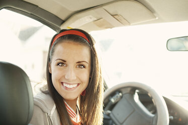 Porträt einer lächelnden Frau, die an einem sonnigen Tag im Auto sitzt - CAVF00620