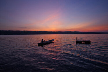Mann rudert Boot auf See gegen Himmel bei Sonnenuntergang - CAVF00669