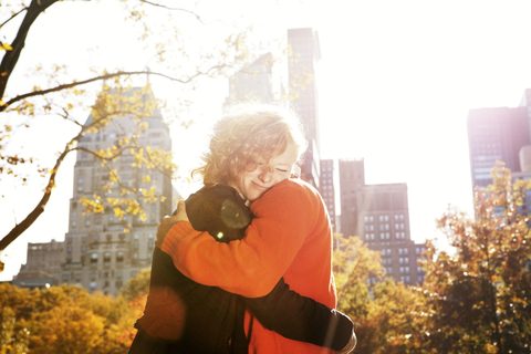 Glückliches junges Paar umarmt sich im Central Park an einem sonnigen Tag, lizenzfreies Stockfoto