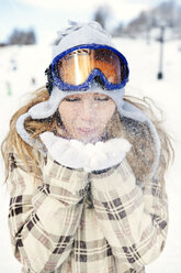 Verspielte Frau in warmer Kleidung beim Schneeräumen - CAVF00772