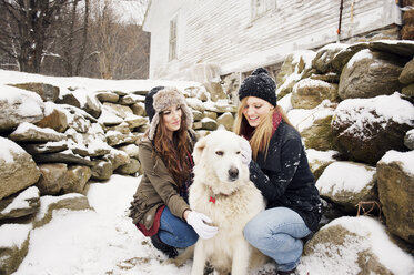 Glückliche Freundinnen mit Hund bei Steinen im Winter - CAVF00779