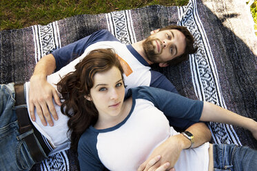 Porträt eines auf einer Decke liegenden Paares im Park - CAVF00786