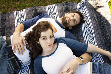 Portrait of couple lying on blanket in park - CAVF00786