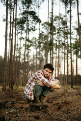 Porträt eines Mannes, der auf einem Feld im Wald hockt - CAVF00792
