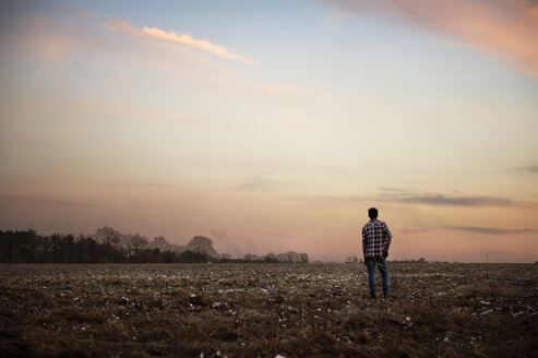 Rückansicht eines auf einem Feld stehenden Mannes gegen den Himmel bei Sonnenuntergang - CAVF00793