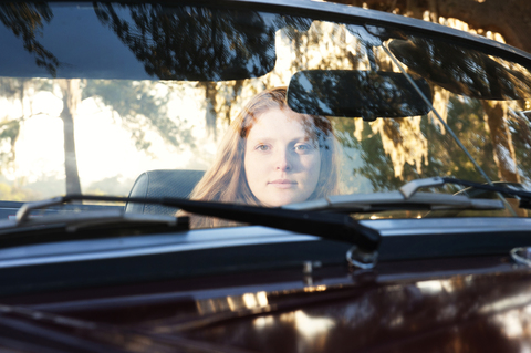 Porträt einer Frau in einem Cabrio durch die Windschutzscheibe gesehen, lizenzfreies Stockfoto