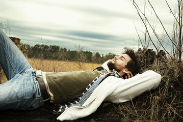 Man relaxing on field against cloudy sky - CAVF00810