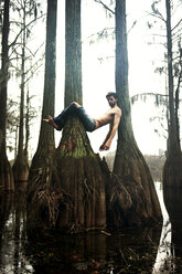 Man relaxing amidst trees over lake in forest - CAVF00815