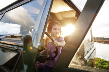 Mädchen auf dem Fahrersitz sitzend an einem sonnigen Tag - CAVF00827